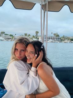 two young women hugging each other on a boat