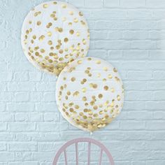 two white and gold balloons hanging from a brick wall