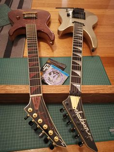 two guitars sitting on top of a table next to each other