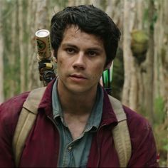 a young man with a backpack and an instrument in his hand is standing in the woods