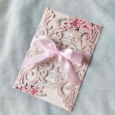 a wedding card with a pink bow on it sitting on top of a blue blanket