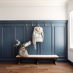 a bench with a hat, coat rack and flowers on it in front of a blue wall