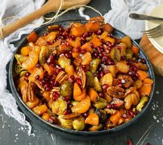 a bowl filled with carrots, brussel sprouts and pecans