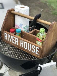 a wooden box that is sitting on top of a bbq with some items in it