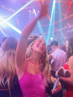 a woman in a pink dress is dancing at a party with her arms raised up