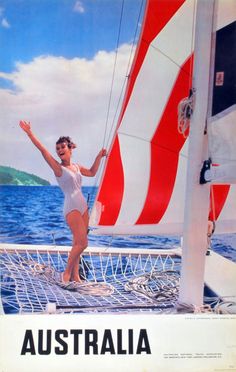 a woman in a bathing suit standing on the front of a sailboat with her arms up