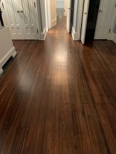 an empty hallway with wood flooring and white trim on the doors leading to another room