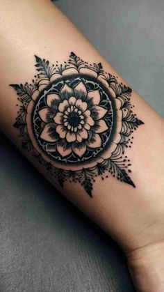 a black and white flower tattoo on the arm, with an intricate design in the center