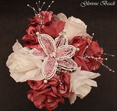 a bridal bouquet made with red and white flowers, pearls and butterfly brooches