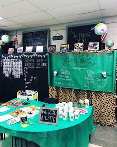 a green table topped with lots of books and drinks next to blackboard covered walls