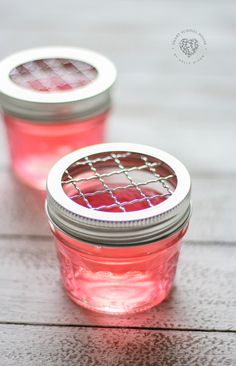 two jars filled with pink liquid sitting on top of a wooden table