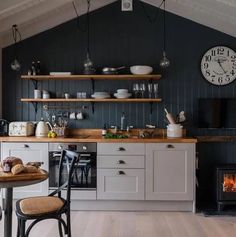 a kitchen with an oven, table and shelves filled with dishes on top of it