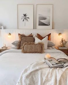 a bed with white sheets and pillows in a bedroom next to two pictures on the wall