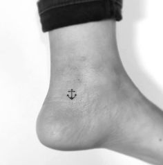 a small anchor tattoo on the ankle is seen in this black and white photo,