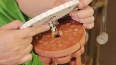 a woman is working on a clay pot with thread and scissors in her left hand