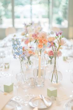 the table is set with flowers in vases and place settings for dinner party guests