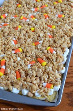 a tray filled with rice krispy treats on top of a wooden table next to candy corn