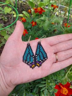 a person's hand holding some beads in their left hand and flowers in the background