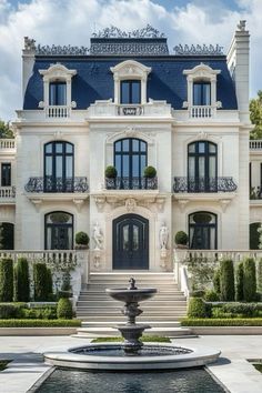 a large white house with a fountain in front of it