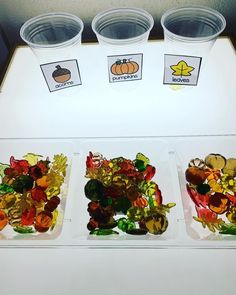 three plastic cups filled with different types of gummy bears sitting on top of a table