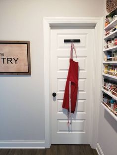 a red apron hanging on the door to a pantry with an empty sign above it