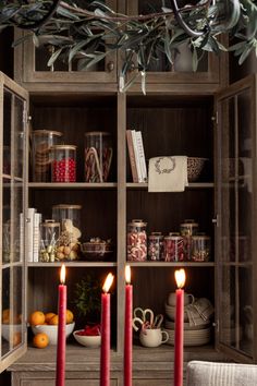 two candles are lit in front of an open bookcase with other items on it