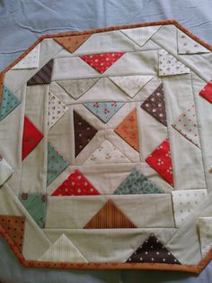 a close up of a quilted table topper on a white cloth covered surface