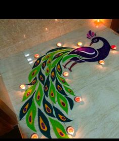 a peacock is on the floor with candles around it and there are lights in front of it