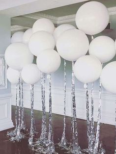 white balloons are floating in the air near some silver foiled trees and mirrors on the wall