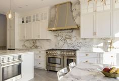 a kitchen with marble counter tops and stainless steel stove top oven, dishwasher, and range hood