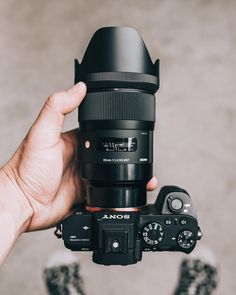 a person holding up a camera in front of their face with the lens attached to it