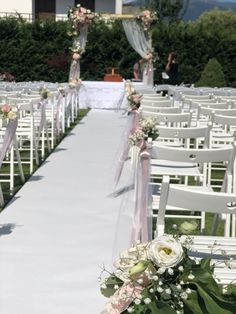 the aisle is lined with white chairs and pink sashes for an outdoor wedding ceremony