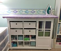 an ironing board sitting on top of a white cabinet next to a book shelf