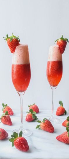 two wine glasses filled with liquid and strawberries