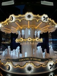 an illuminated carousel with white dresses on display