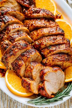 sliced pork and oranges on a white plate