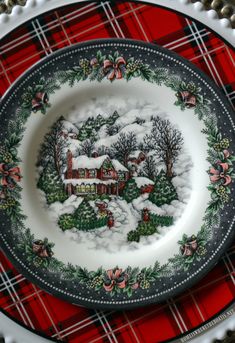 a plate with a christmas scene on it sitting on a plaid tablecloth covered placemat