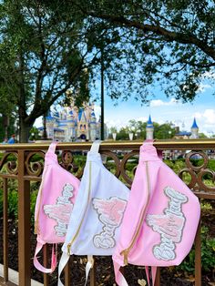 two pink and white backpacks are hanging on a rail in front of a castle