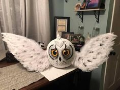 an owl mask with wings on top of a table in front of a mirror and pictures