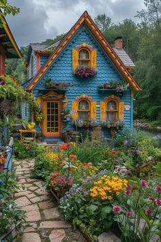 a blue house with yellow shutters and flowers around it's front yard area