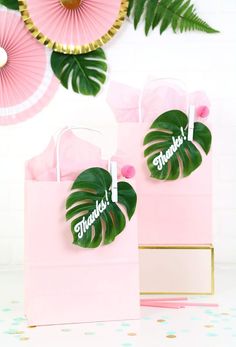 two pink paper bags with monster leaves on them and the words thank you in green lettering