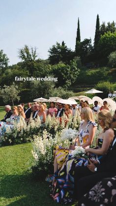 a group of people sitting on top of a lush green field next to umbrellas