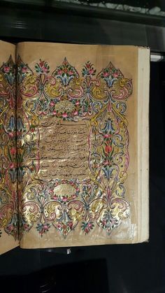 an open book with arabic writing on the cover and gold foiled paper covering it