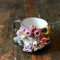 a ceramic cup with flowers on it sitting on a wooden table next to a candle holder