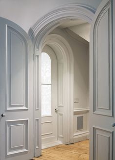 an archway leading to another room with wooden floors and white walls, along with hardwood flooring