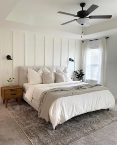 a bedroom with a bed, ceiling fan and rug on the floor in front of it