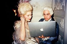 a man and woman looking at an apple laptop