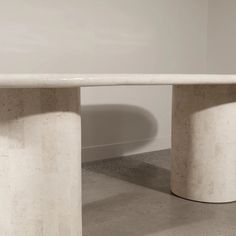 two white marble pedestals sitting next to each other in a room with concrete flooring