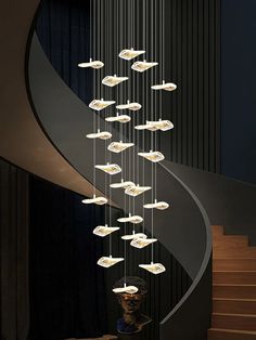 an artistic chandelier hanging from the ceiling in front of a spiral stair case