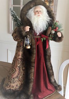 a statue of santa claus holding a bell on top of a wooden table in front of a window